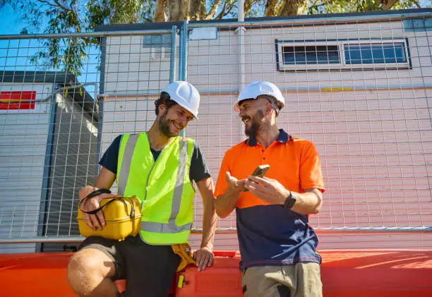 Construction workers verifying credentials on phone